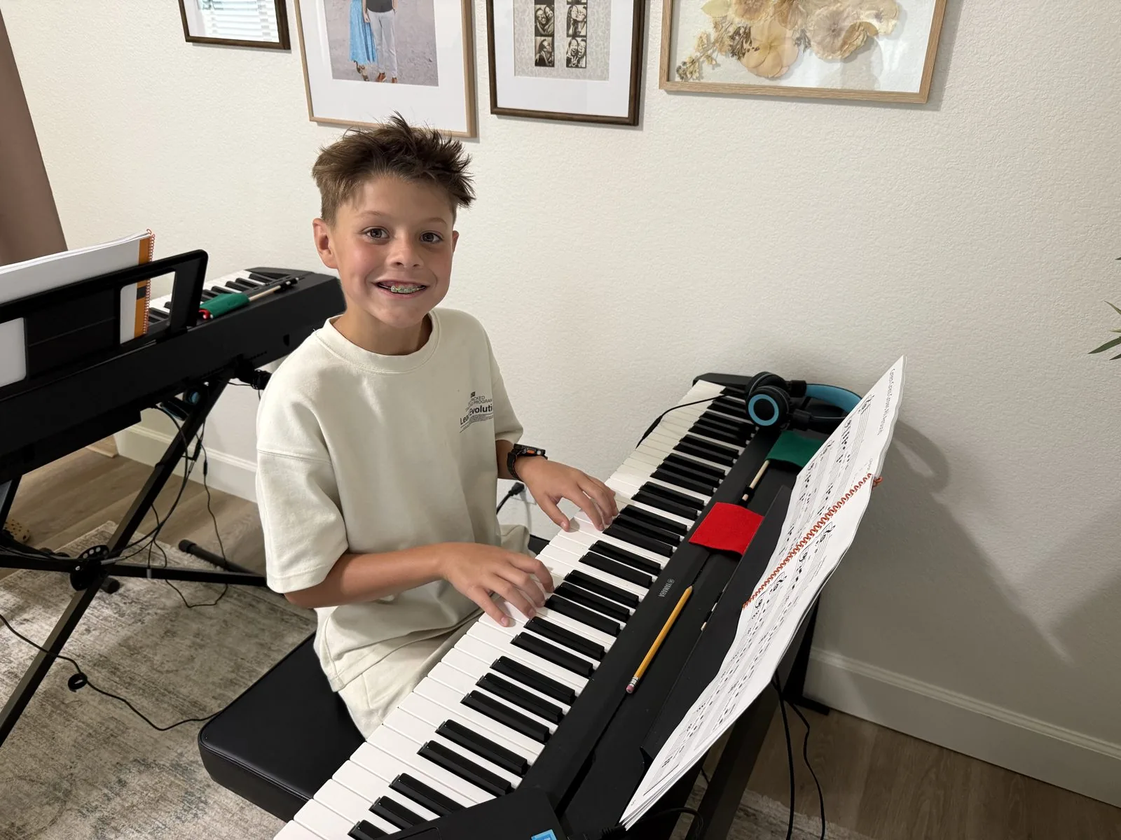 A student smiling while playing the keyboard during a piano lesson